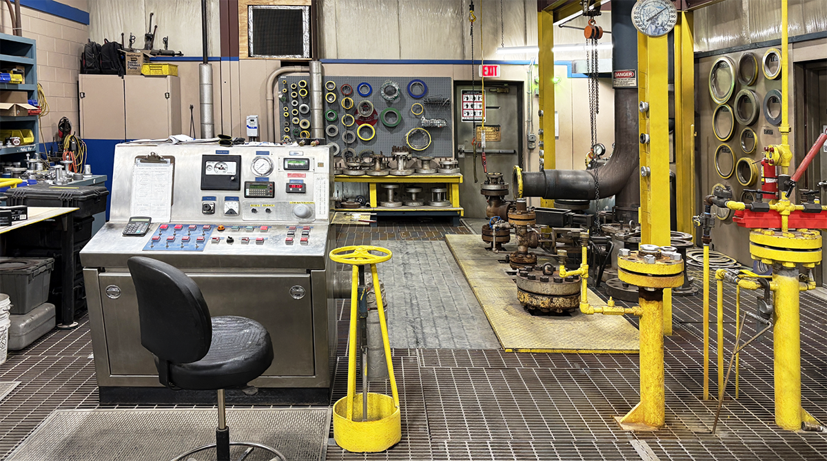 Industrial mechanical testing and service facility with control panel, piping systems, and maintenance equipment.